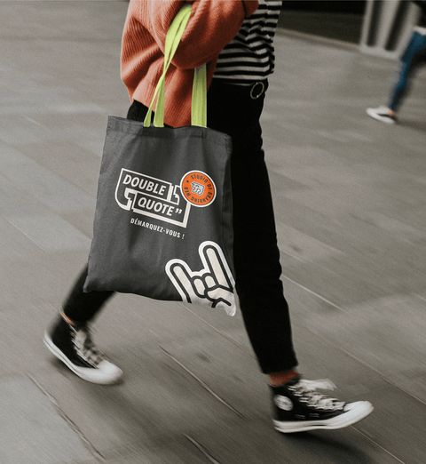 Personne marchant avec un tote bag Double Quote à l'épaule.