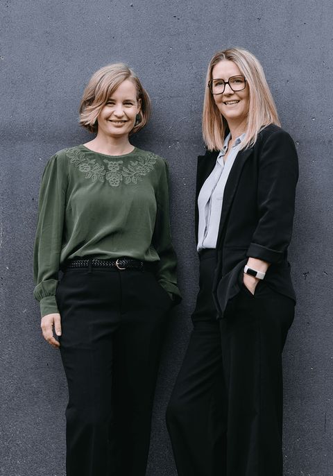 Moira McDonagh et Georgina Eaton, dirigeantes de Let's CONNECT, côte à côte devant un mur de béton.